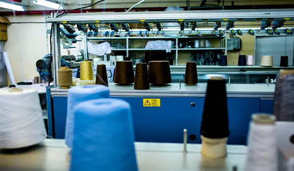 Woman using a sewing machine in a garment facility, showcasing streamlined operations with garment manufacturing ERP software.